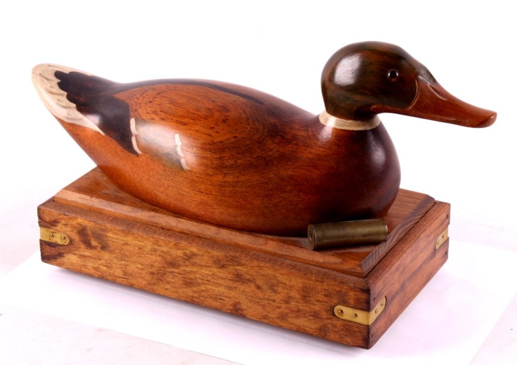 Wooden Duck Decoy Box This is a wooden duck decoy: This is a wooden duck decoy box. The duck is made from solid wood and is hand painted. It is mounted to the top of the wooden box. Next to the duck is an antique brass Winchester shotgun shell. The bo