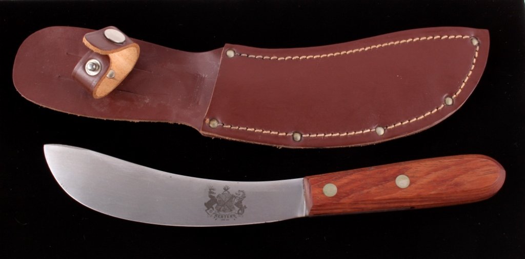 Herter's Hudson Bay Skinning Knife: The lot features a Herter's Hudson Bay hunters skinning knife with leather sheath. The knife has a carbon steel blade, wood handle, and a leather sheath. The piece shows good condition with some wear