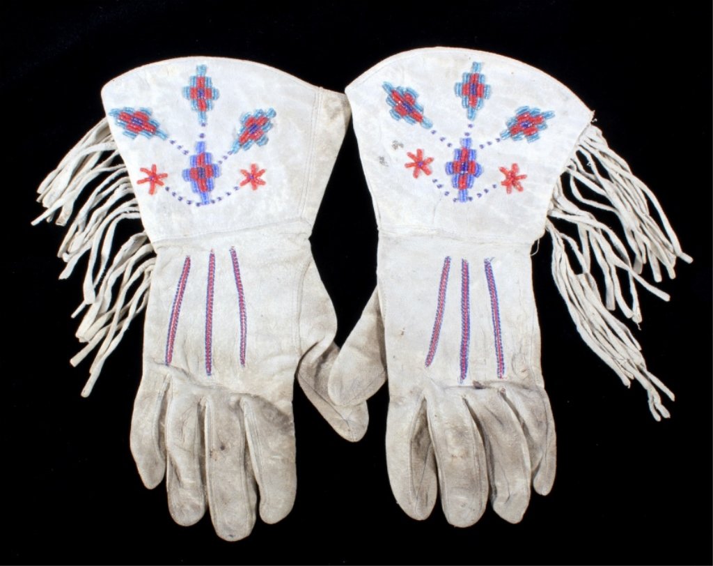 Northern Plains Beaded Gauntlet Gloves c. 1940: The lot features a set of Indian tanned hide gauntlet gloves with wonderful cut and seed glass trade bead work and long cut fringe. The set is from the Northern Plains Native American Indians from cir
