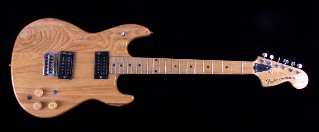 Fender Stratocaster Electric Guitar: This is a Fender Stratocaster electric guitar. The guitar features a wooden body, neck, and headstock with a natural finish. The guitar appears to be in good overall condition. There is some rust on t