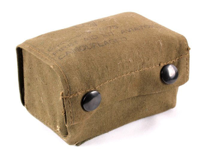 Vietnam Era Aviator First Aid Kit: This is a new old stock aviator first aid kit from the Vietnam Era. The kit comes in an olive drab pouch. Contained in the kit is a muslin bandage and a sealed box with additional bandages, motion sic
