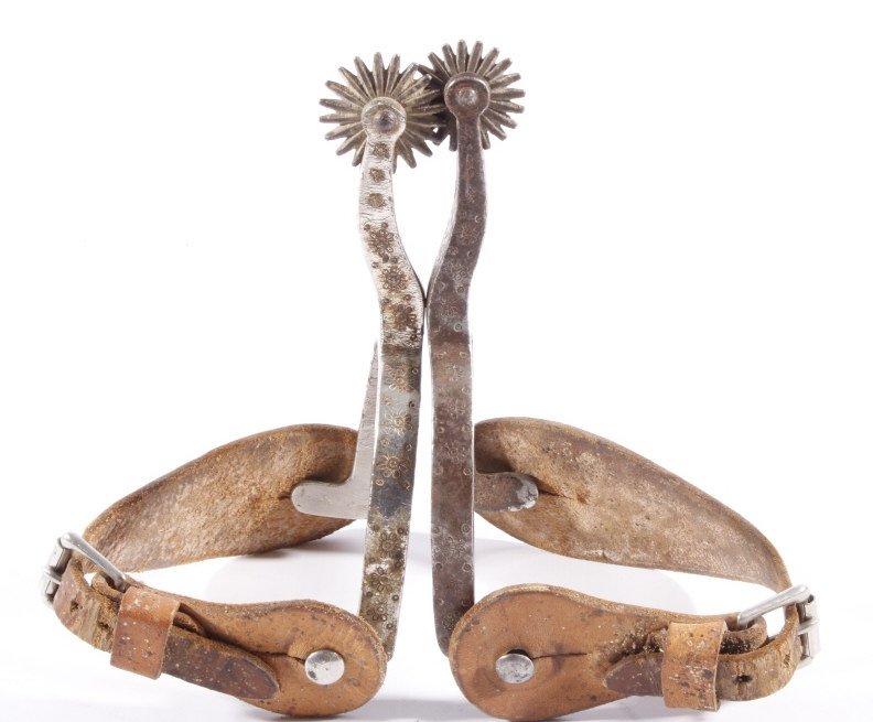 August Buermann Western Spurs c. 1890-1926: The lot features a set of August Buermann Western Spurs from circa 1890-1926. The spurs have a stamped floral design on the hand forged steel construction with nickel finish. The spurs come with early