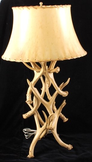 Deer Antler Table Lamp with Rawhide Shade: This is a deer antler table lamp with a rawhide shade. The antlers are cast and make a wonderful base for this rustic style lamp. The shade is made from rawhide laced with leather. A great piece of We