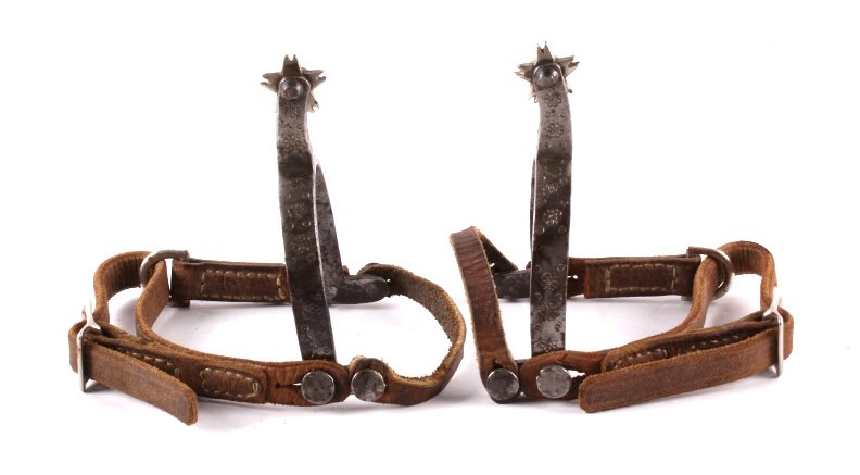 August Buermann Western Spurs c. 1890-1926: The lot features a set of August Buermann Western Spurs from circa 1890-1926. The spurs have a stamped floral design on the hand forged steel construction. August Buermann sold out to North & Judd in