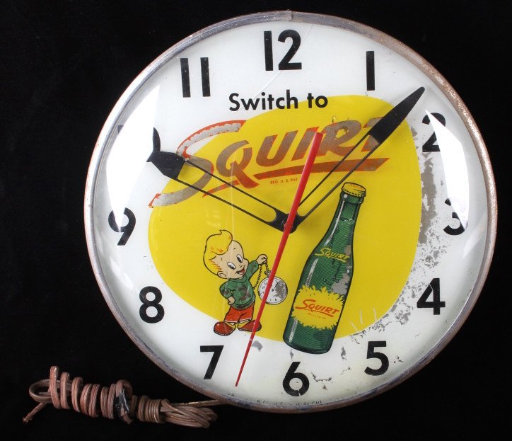 Rare Vintage Squirt Wall Clock C.1960's: This lot features a Vintage Squirt wall clock from the 1960's. The clock shows original wear (crack in the glass) and is in working condition (lights with cord and clock works) It measures 15" D x 4" 