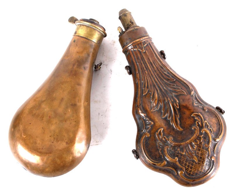Antique Brass And Copper Gun Powder Flasks: These are antique gun powder flasks. They are made from brass and copper. One flasks has a adjustable spout and the other looks to be missing. One flask shows a beautiful leaf design and the other has
