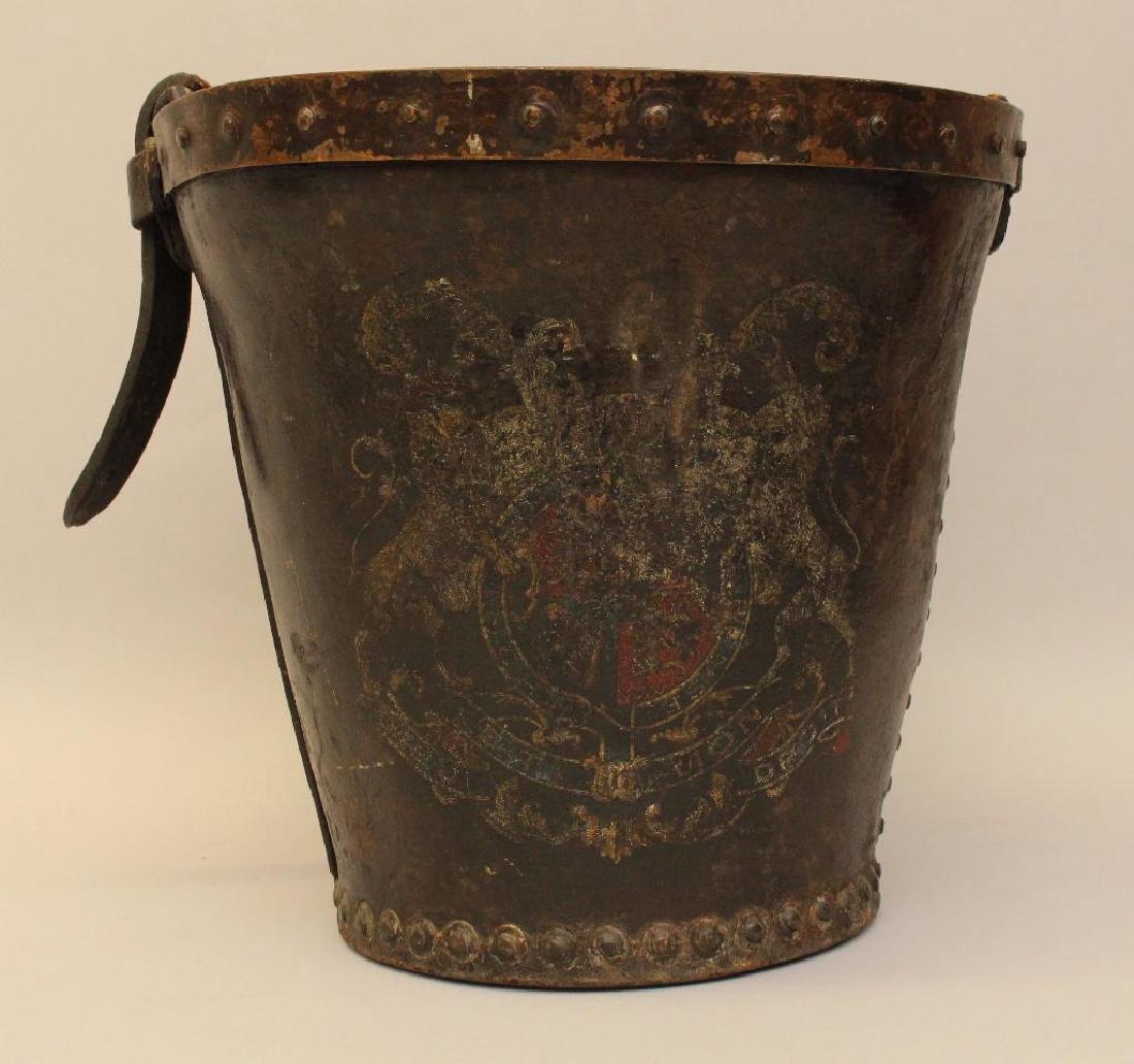 English Leather Fire Bucket: Leather bucket decorated with royal coat of arms. Missing handle, though buckle and part of strap remains. 11.5"h x 11.5" round.