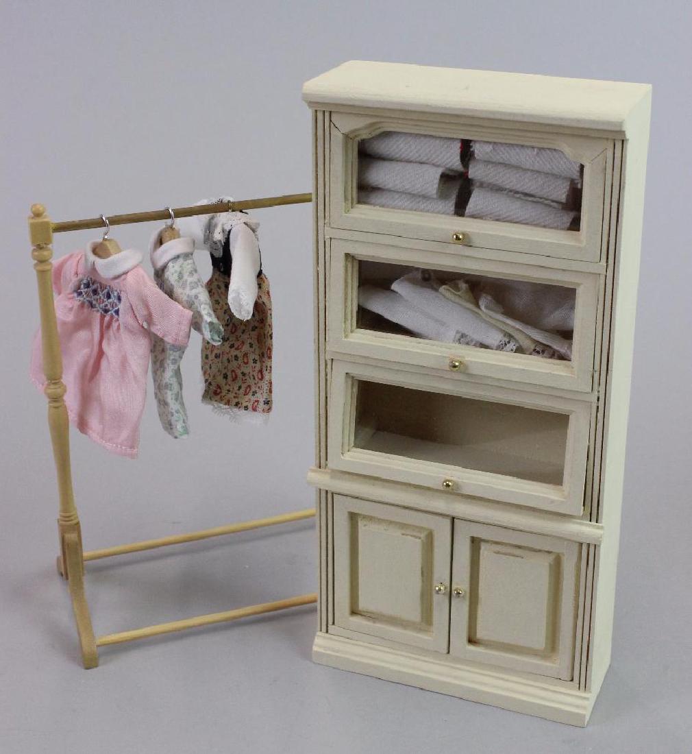 3 little girl dresses, dress rack and tall display case: 3 little girl dresses Heidi Ott and Heidi Ott dress rack and Tall display case with baby linens by Falcon; pink sweater by Taller Targoni