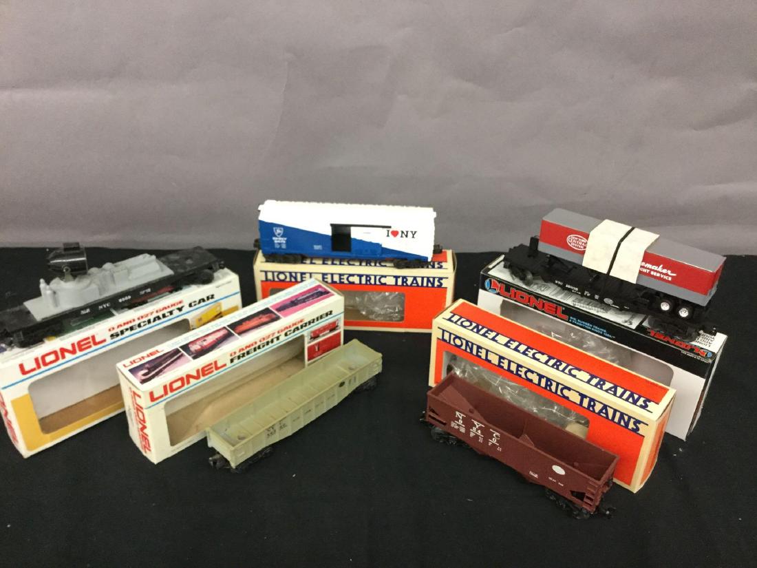 Grouping of five Lionel Trains: New York Central operating hopper 6-9240, New York Central searchlight car 6-6529, New York Central flag car with trailer 6-16335, New York Central long gondola 6-6250, Delaware and Hudson, New York b
