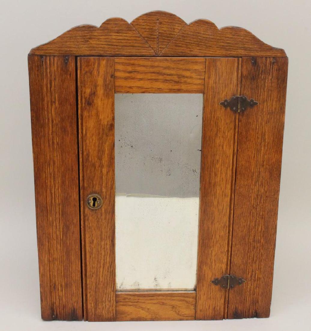 Hanging Corner Cupboard: Oak with a shaped cornice and a single mirrored door, 18"h x 13.5"w x 9.5"d.
