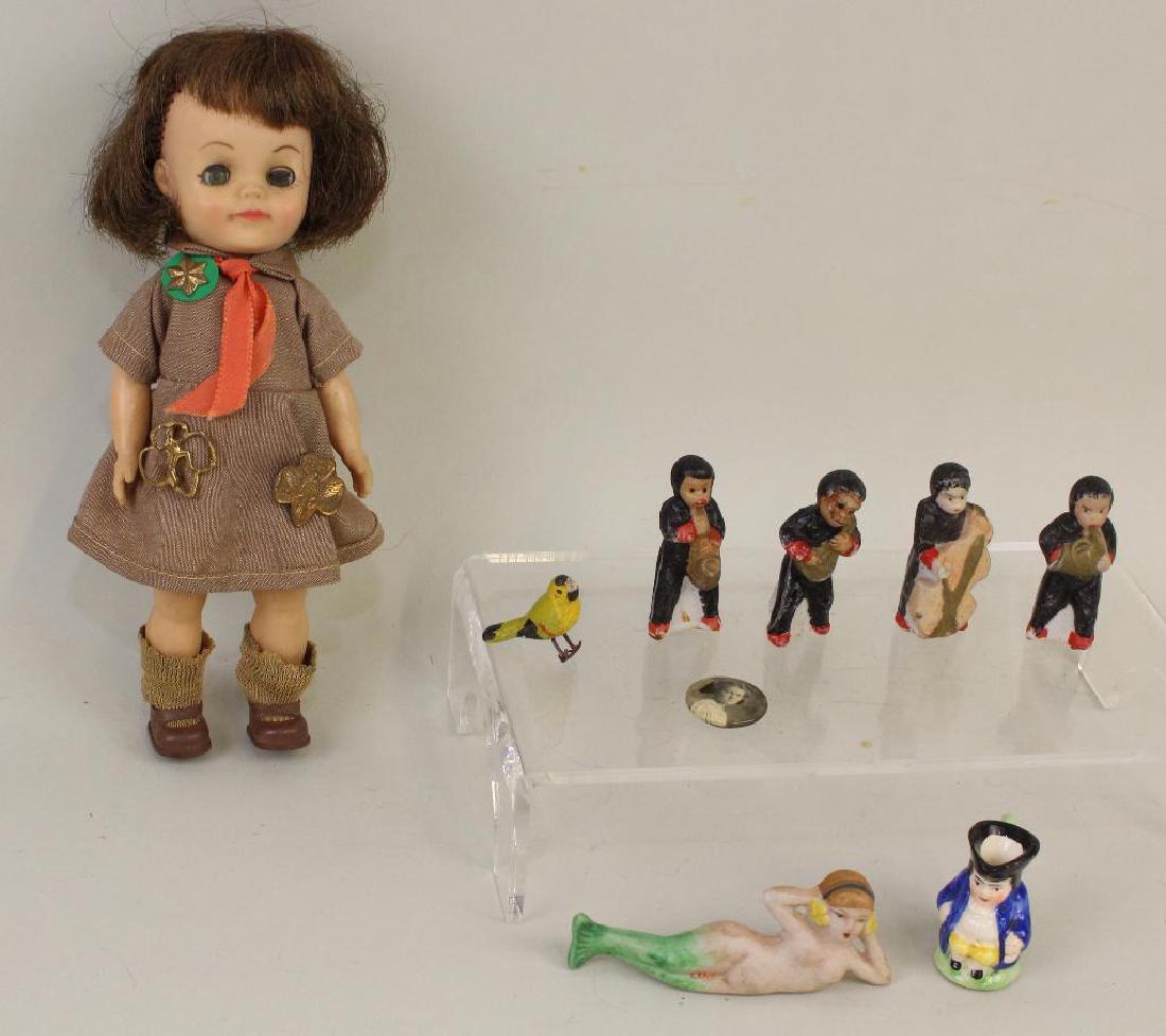 LOT: 8" EFFANBEE BROWNIE DOLL, ANTIQUE MINIATURES.: Vinyl "Brownie"- has her uniform but missing her beanie. She has (3) different Girl Scout pins on her uniform. Condition: age discoloration. Miniatures - 4 pc. porcelain band; figures could be Black o