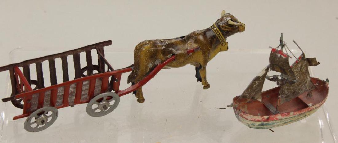 PAIR OF METAL TOYS INC. PENNY TOY; SHIP.: German Penny Toy Cow pulling wagon. Marked Ges. Gesch. Condition: paint loss on cow from wagon rubbing. Painted metal ship with brass sails. Condition: paint loss.