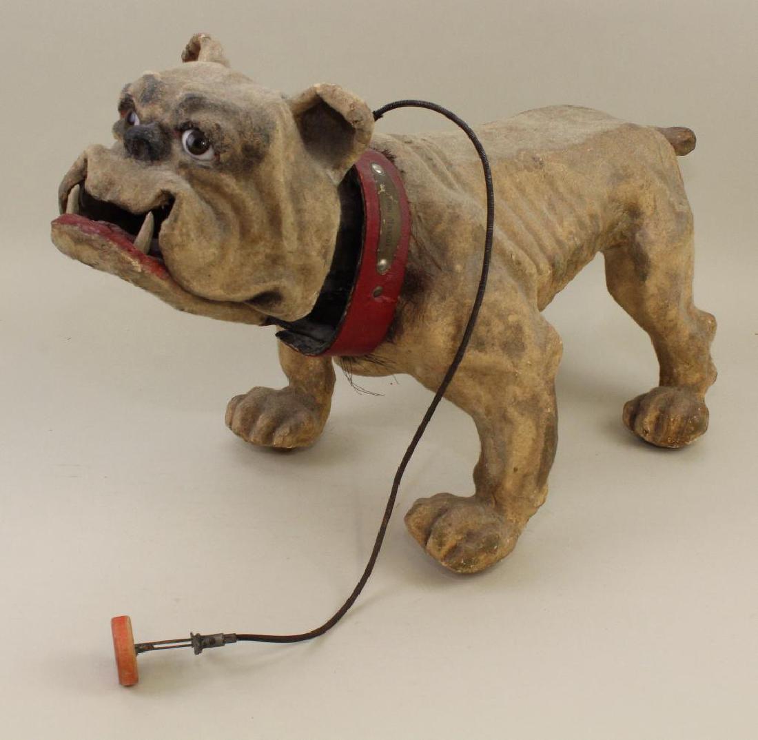 26" L x 15" T PAPIER MACHE "BULLDOG MASCOT" DOG.: Ca 1890. Possibly French but may be from the Sonneberg region of Germany. Large brown glass eyes, nodding head with hinged jaw with sculpted teeth. Original red collar reads: Bulldog Mascot". Wooden w