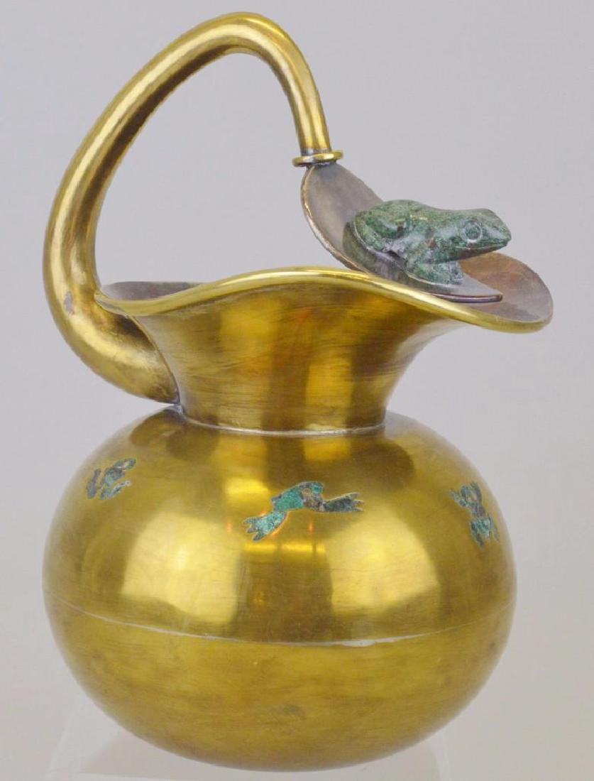 Los Castillo Malachite and Brass Frog Pitcher: Carved malachite frog applied to the spout, with inlaid malachite accents in the form of frogs in various positions. Marked Los Castillo. 9.5"h x 7"w 