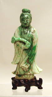 Chinese Carved White and Apple Green Jade/Jadeite: Late 19th /early 20th C., standing figure with flowing robes, serene facial expression, and holding a scepter. Finely carved white stone with many green inclusions. On carved wood base. Traces of