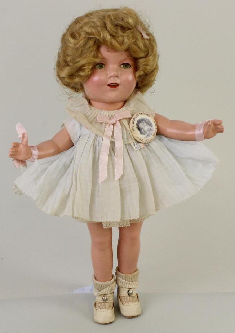 13" ALL ORIGINAL TAGGED COMPOSITION IDEAL SHIRLEY: This is an original owner doll. Uncombed honey blonde mohair wig. Dressed in tagged pale blue pleated organdy dress tied to her wrists with pink silk ribbon. 1 Pc. cotton underwear. Ivory oilcloth cen