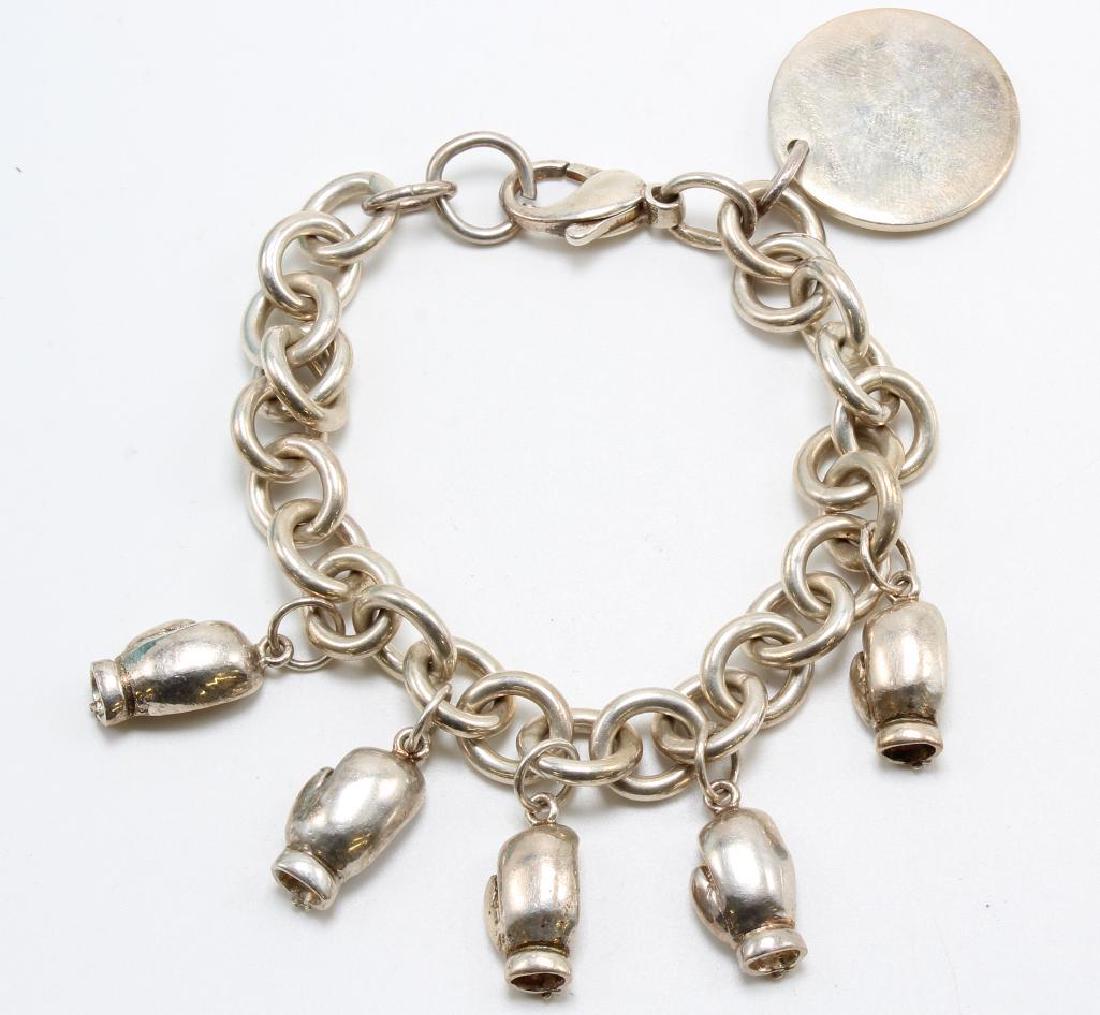 Tiffany & Co., AC. Charm Bracelet with Charms. Sterling: Bracelet is unmarked 7 1/2" long with 10mm wide quality soldered links and claw clasp. Unsoldered jump rings have been added. Features (5) boxing glove charms by AC and (1) disc "MUST WIN 2001" by Tif