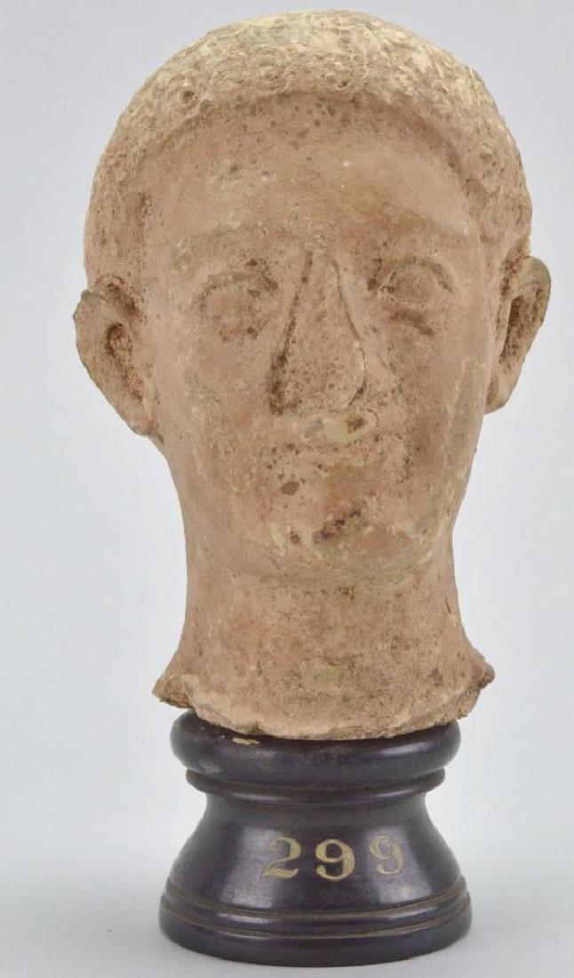 Greek Terracotta Head: 3-5th c. B.C., socle with hand painted "299", red inventory number, CP. 2203. 7.25"h x 4"w x 4"d