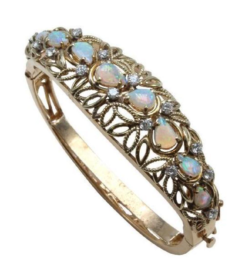 14K Yellow Gold Hinged Bangle Bracelet with Opals and: Hinged with pressure tongue clasp, safety catch and permanent stabilizing sizing bar. 2 X 1 3/4" I.D. with bar. The bracelet would be 2" round without inner bar. Features (8) graduated 6 X 4mm - 7 X 