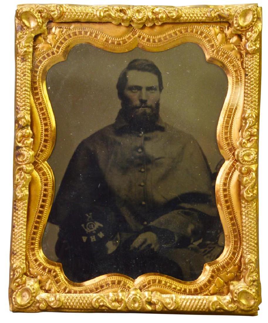 Civil War Tintype of Private Amos E. Bradley-12th New: Ninth plate tintype of Civil War soldier Private Amos E. Bradley, Company K, 12th New Hampshire Volunteer Infantry. Image shows Bradley knees up wearing a great coat holding his kepi with top showing 