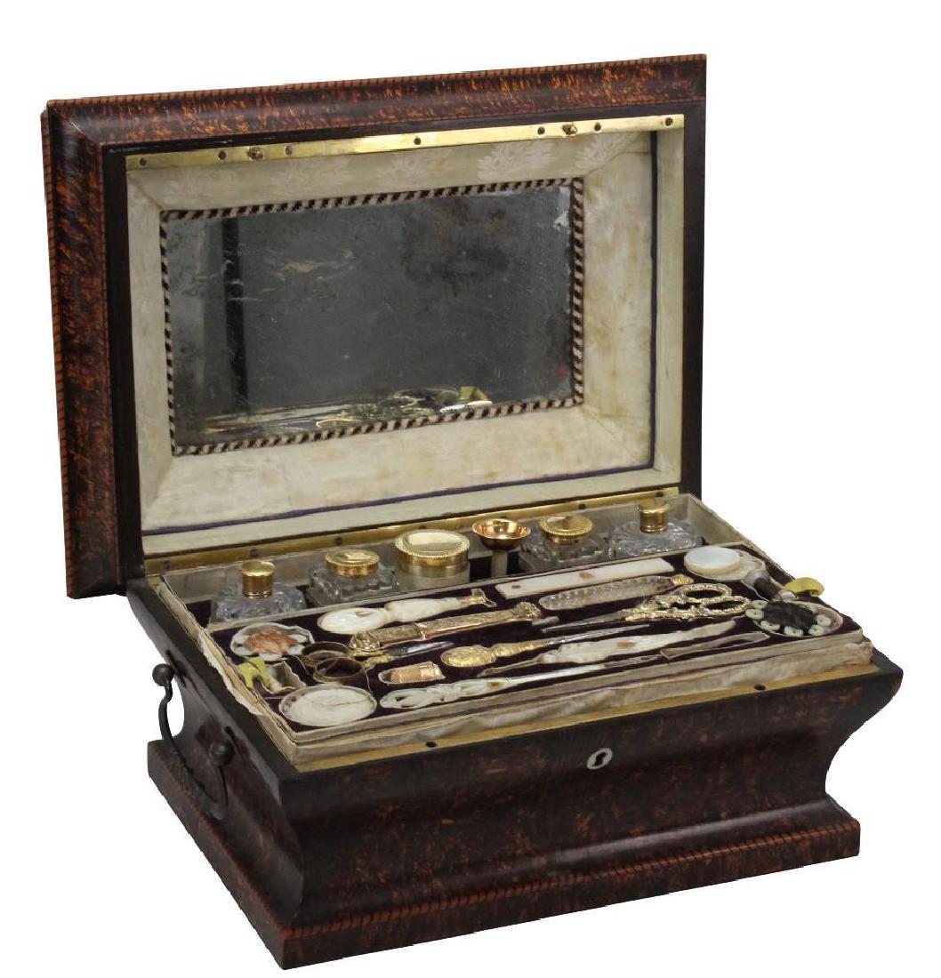 19th C. Travel Sewing Case: French, Amboyna wood case, c.1819-1838. 14k gold thimble, mother of pearl handled accessories and folding measure, gold plated thread scissors and lids to crystal bottles.