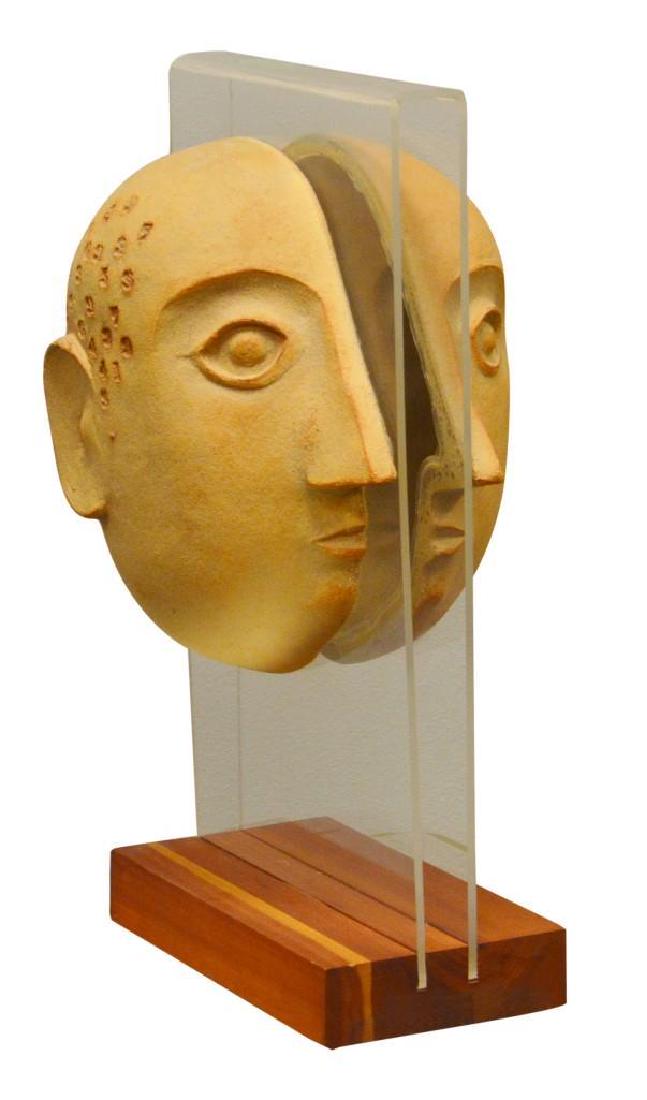 David Gil (20th century): For Bennington Potters - Art pottery sculpture in the form of a split head with numbers mounted to lucite on wooden base. Impressed to inside of right side of head. 19.25"h x 9"w x 10"d