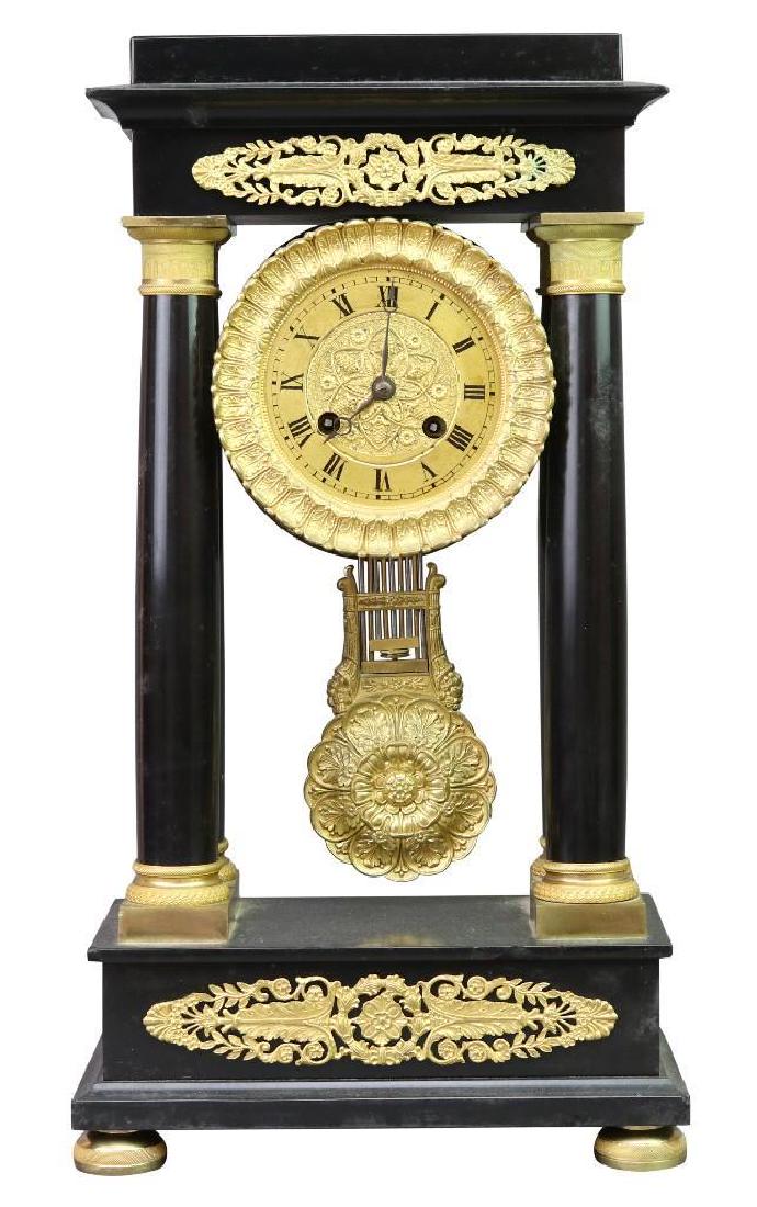 Portico Mantel Clock: French, circa 1830-1840 Ebony and gilt 17 1/4" H x 9 1/2" W x 4 3/4" D Louis Phillipe period, ebony case with four columns, 8 day movement with bronze face with roman numerals, gilt ormolu decoration,