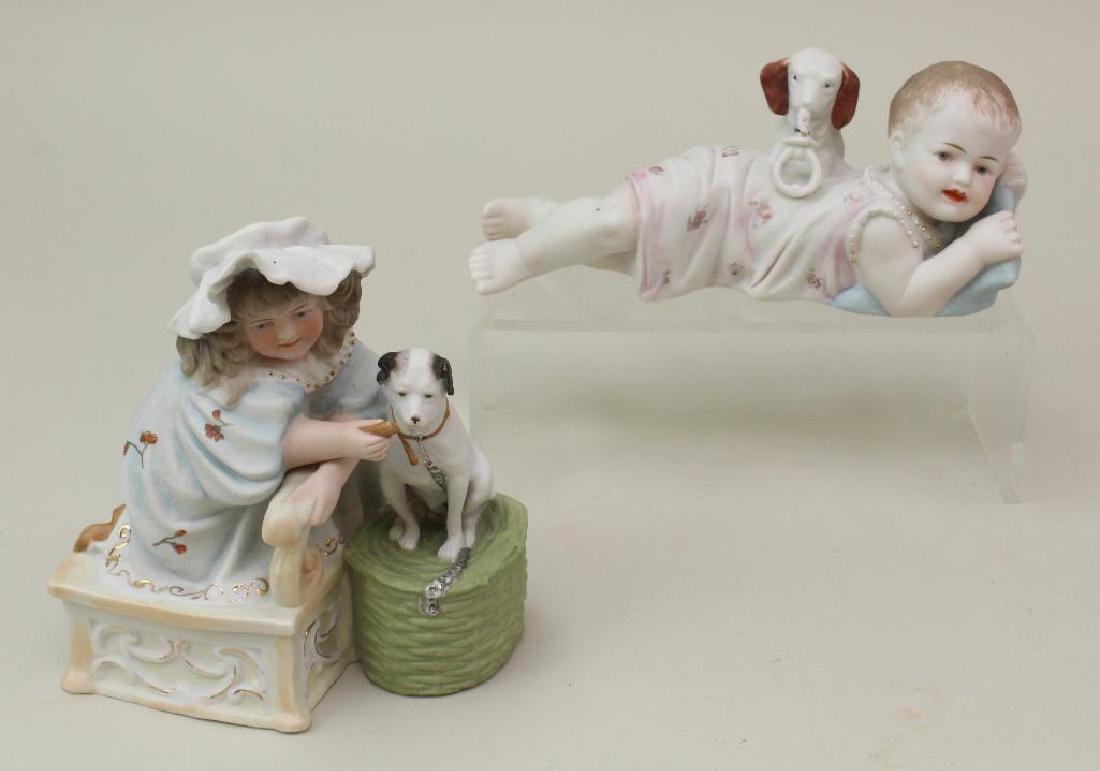PAIR OF ANTIQUE FIGURINES: PIANO BABY AND OTHER.: 8" L. Unmarked reclining baby on stomach wearing floral night gown. Leaning on blue pillow, the dog is holding toy in his mouth and resting against the baby's back. Condiiton: paint loss on toy otherw