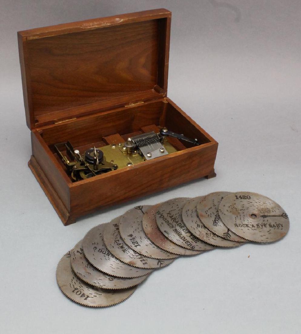 Thorens Disc Music Box: Disc music player in a mahogany box with original label and (10) 4.5" discs, 4" H x 10" W x 6.25" D