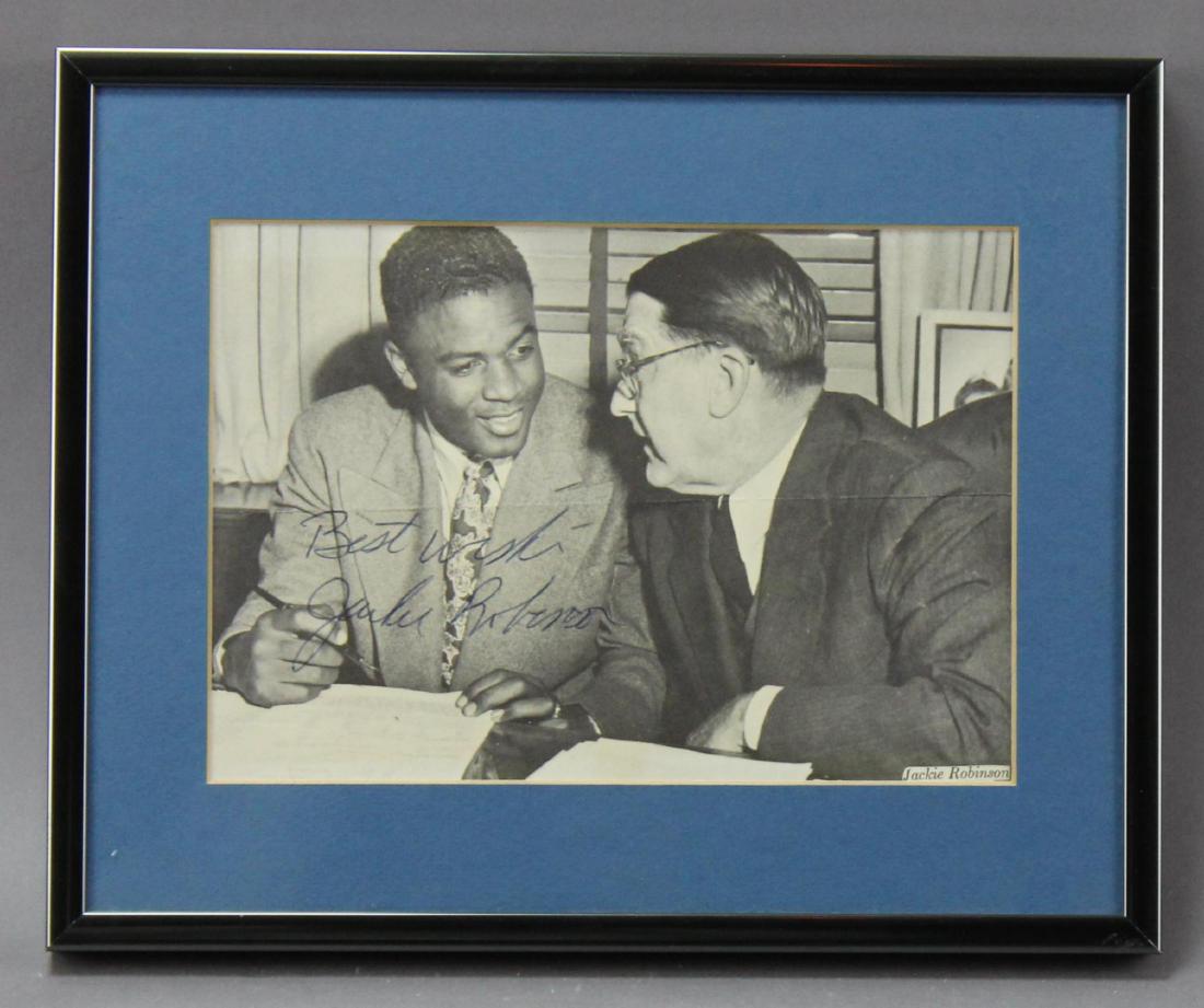 Jackie Robinson Autograph: Autograph of baseball great Jackie Robinson (1919–1972) the first African American to play in Major League Baseball. Autographed newspaper image of Robinson with Branch Rickey, president of the Broo