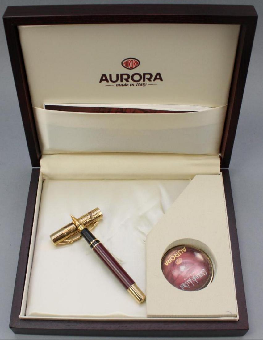 Aurora Leonardo da Vinci Fountain Pen: Gold plated with burgundy lacquer barrel and tapered 18k gold nib. Original box 2.5"H x 9.5"W x 8.5"D