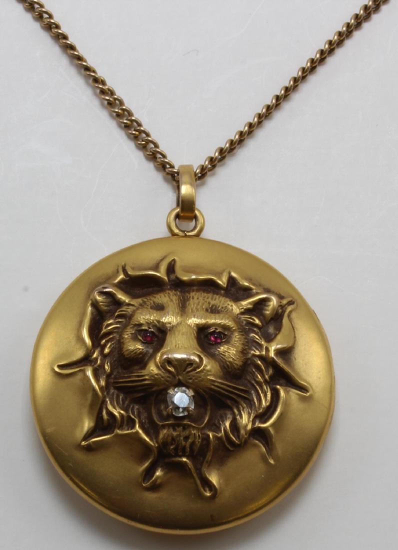 Pendant on Chain. Locket with Lion's Head. Diamond. 10K: 21" long chain with 30.5mm diameter locket. Lion features (1) 2.5mm mine cut Diamond in mouth and red cabochon eyes. 12.8gtw.