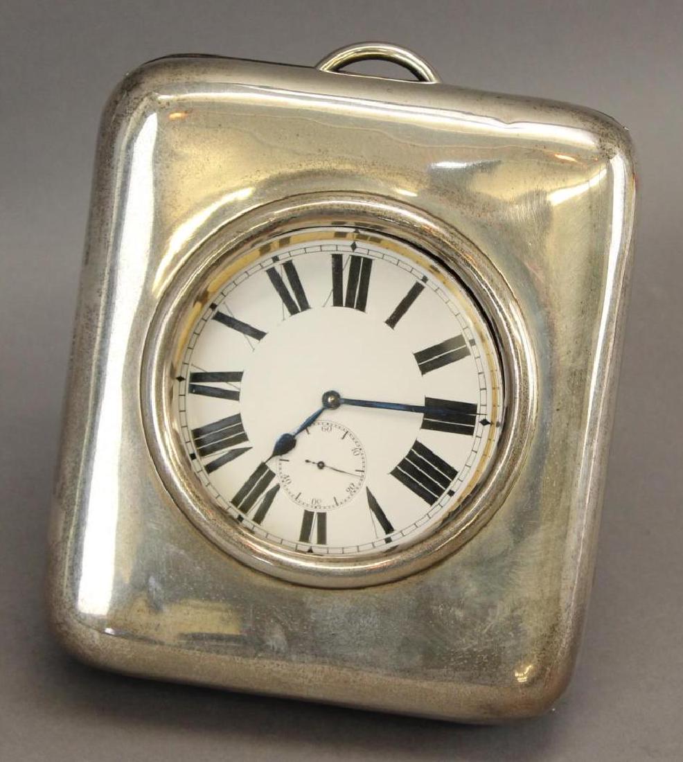 William Comyns Cased Clock: Pocket watch style clock in easel back sterling silver watch case. Case is hallmarked William Comyns and Sons, Ltd, London, and measures 6" x 7".