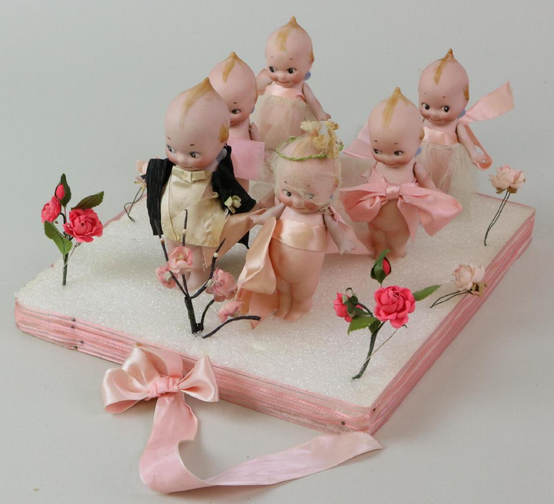LOT OF KEWPIE.: Wedding party. Lot of (6) antique all bisque standing Kewpies. Groom is 5", bride 4 1/4", bridesmaids 4 1/4". All have strung arms only. Groom is wearing a crepe paper jacket, silk ribbon shirt/vest. 
