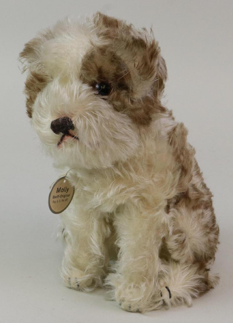 9" TAGGED ANTIQUE MOHAIR STEIFF "MOLLY" DOG.: Varigated long ivory and brown tipped mohair sitting dog with amber glass eyes. Swivel head. Round tag reads: MOLLY Steiff Original Reg. U.S. Pat. Off. Back has a penciled date of July 13, 1927. Silve