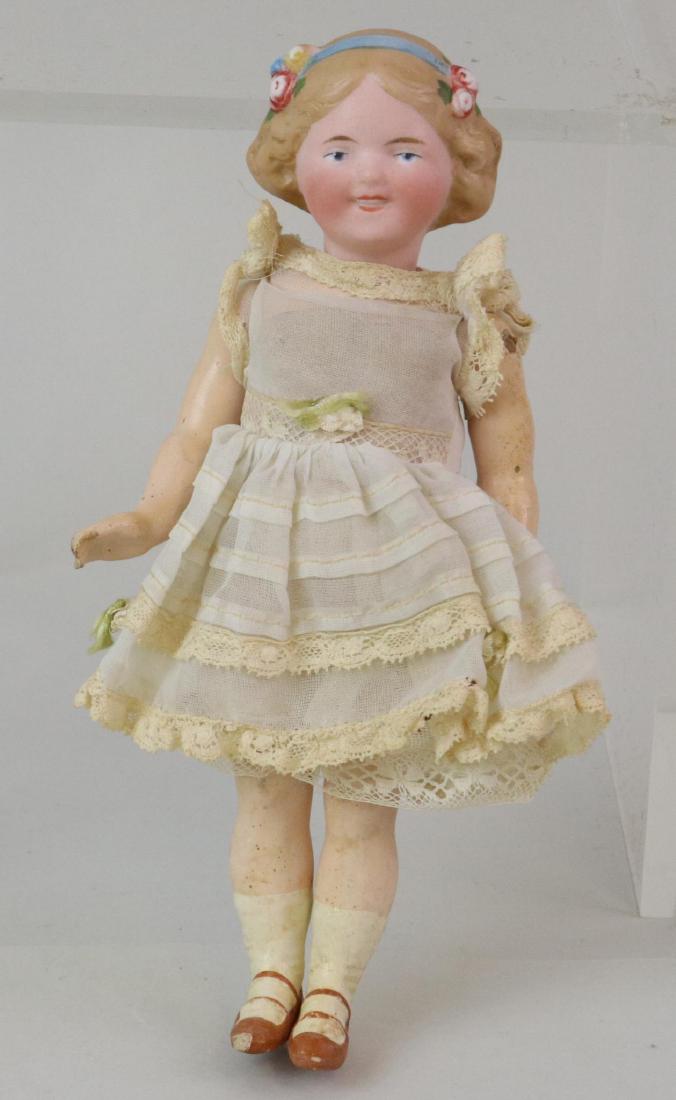 ANTIQUE BISQUE HEAD DOLL(S), 12" AND UNDER.: 7" 68 13/0 Doll with molded painted features (Goebel type): integlio eyes, open/closed mouth, blonde hair with blue head band and flowers. 5 Pc. papier mache body with painted tan heeled 2-strap shoes