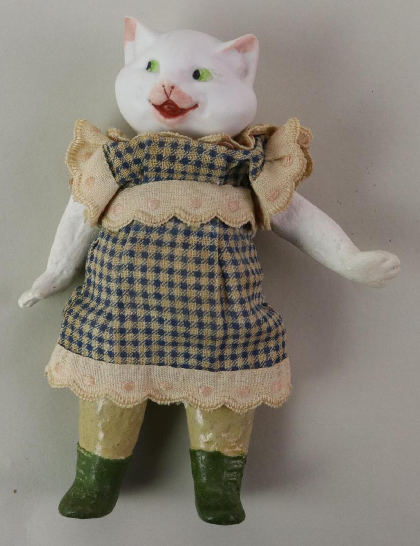 ANTIQUE BISQUE HEAD DOLLS(S), 12" AND UNDER.: 6" Novelty doll with white bisque cat head marked: 5/0 91 HEUBACH symbol ?? 5 Pc. papier mache body with painted green boots. Antique clothing. Condition: nothing observed on bisque.