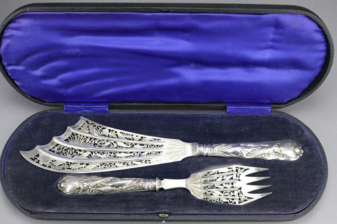 English Sterling Silver Fish Server: Cased set with pierced panels depicting fish, shells and various flora on chaste hollow handles adorned with dolphins. In original silk and velvet fitted case. Hallmarked London 1908, makers mark is M
