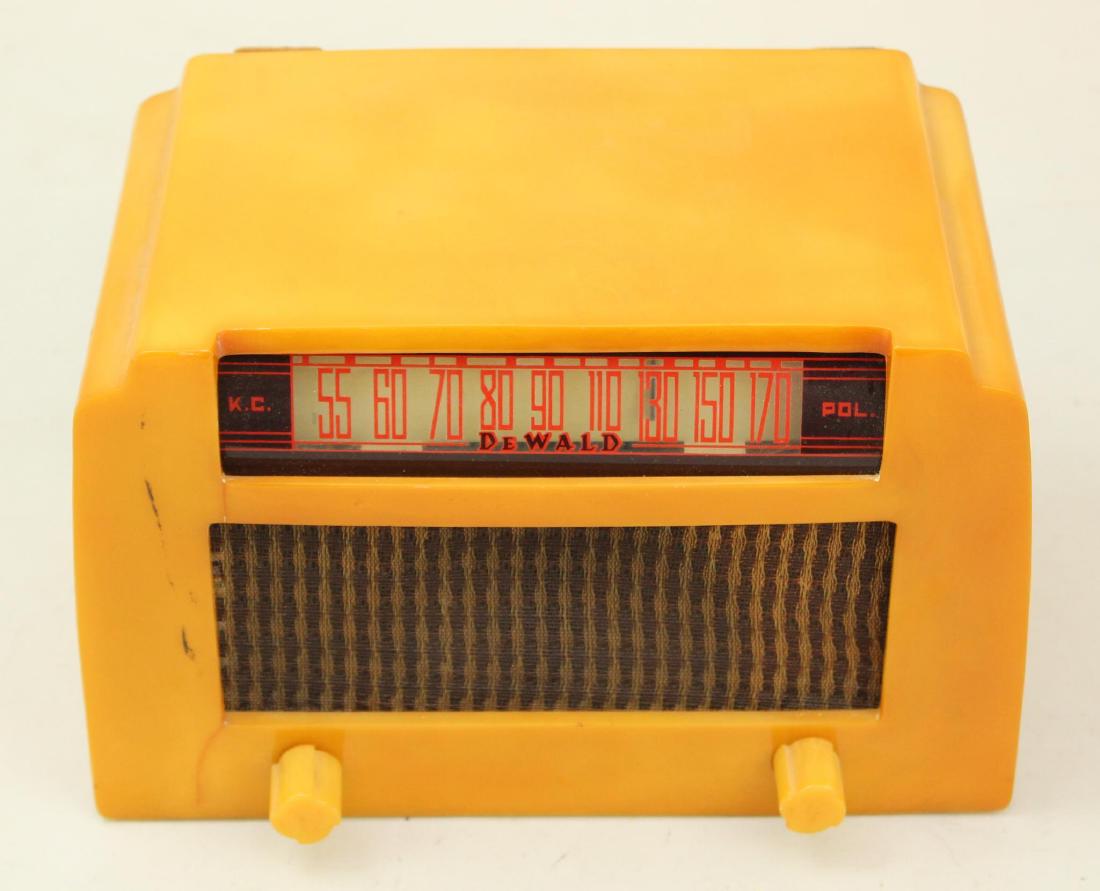DeWald Catalin Radio: Model A502. c.1938. Yellow with cloth grill. Surface crack to left of volume knob. Does not appear to go all the way through. Small crack bottom left of dial face. Approx. 1". Cord intact. Powers on.