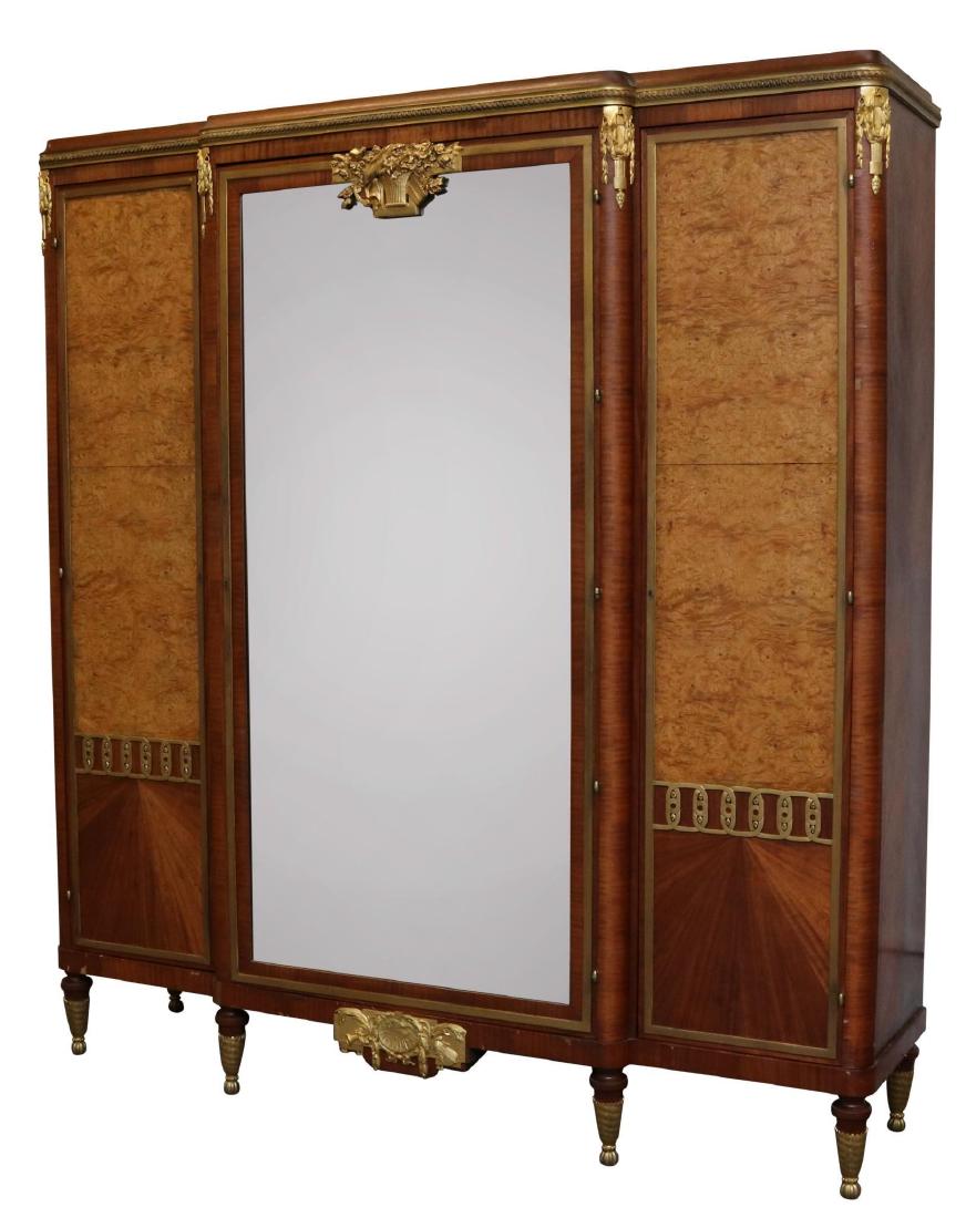 Mahogany Veneered and Ormolu Mounted Wardrobe: Sea scroll mounted top with a cornucopia and bell flower mounted mirrored center door flanked by two burl-wood veneer and mounted doors on turned tapered and mounted feet. 87”h x 77”w x 22”d