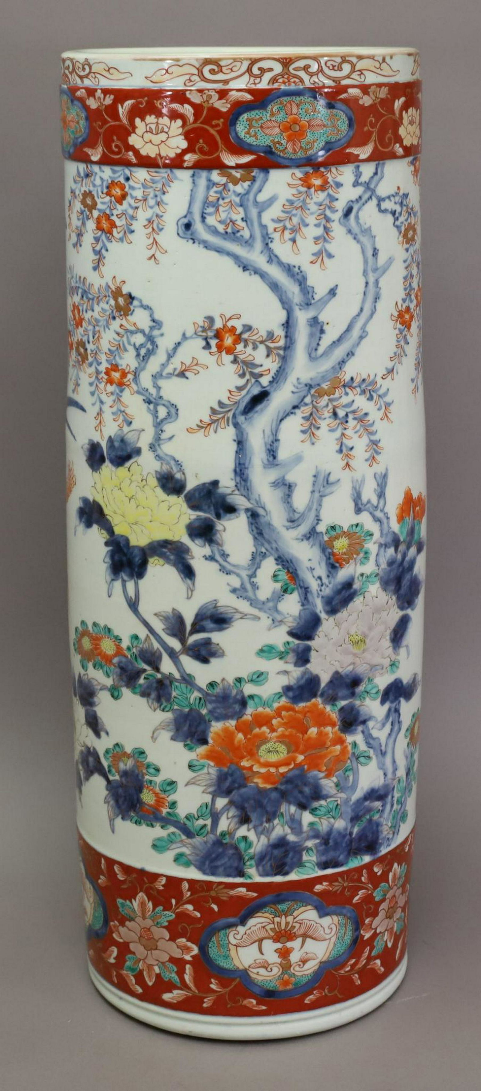 Japanese Imari Porcelain Umbrella Stand: late 19th/early 20th Imari with red bands with underglaze blue decoration, central section decorated with birds in flight amongst flowers and blossoms. Signed. 24"h x 7"round.