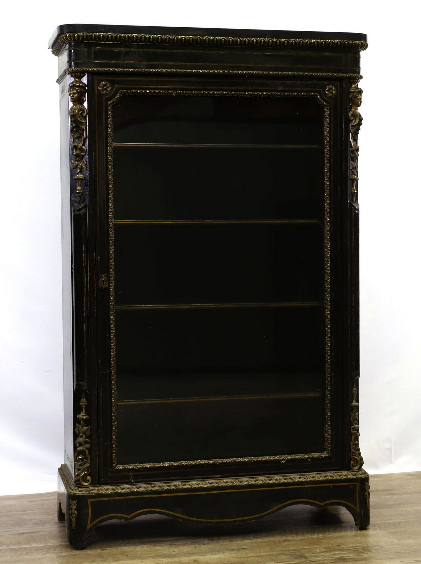 French Ormolu Mounted and Ebonized Bookcase: Marble top with ebonized wood and banded boulle inlay. Figural, floral, and repeating pattern mounts on a shaped apron and feet. 54.5"h x 33"w x 13"d