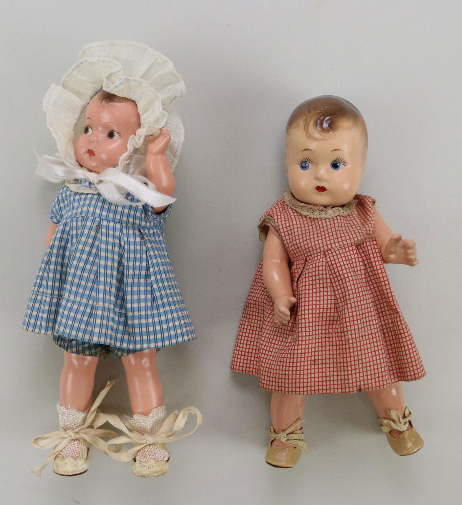 PAIR OF COMPOSITION TODDLER DOLLS.: 7 1/2" R & B Doll Co. 8" Effanbee BABY TINYETTE. Both dolls have painted features/hair, with side glance eyes. Swivel necks with 5 pc. bodies. Both are wearing check dresses with matching teddies. Onl
