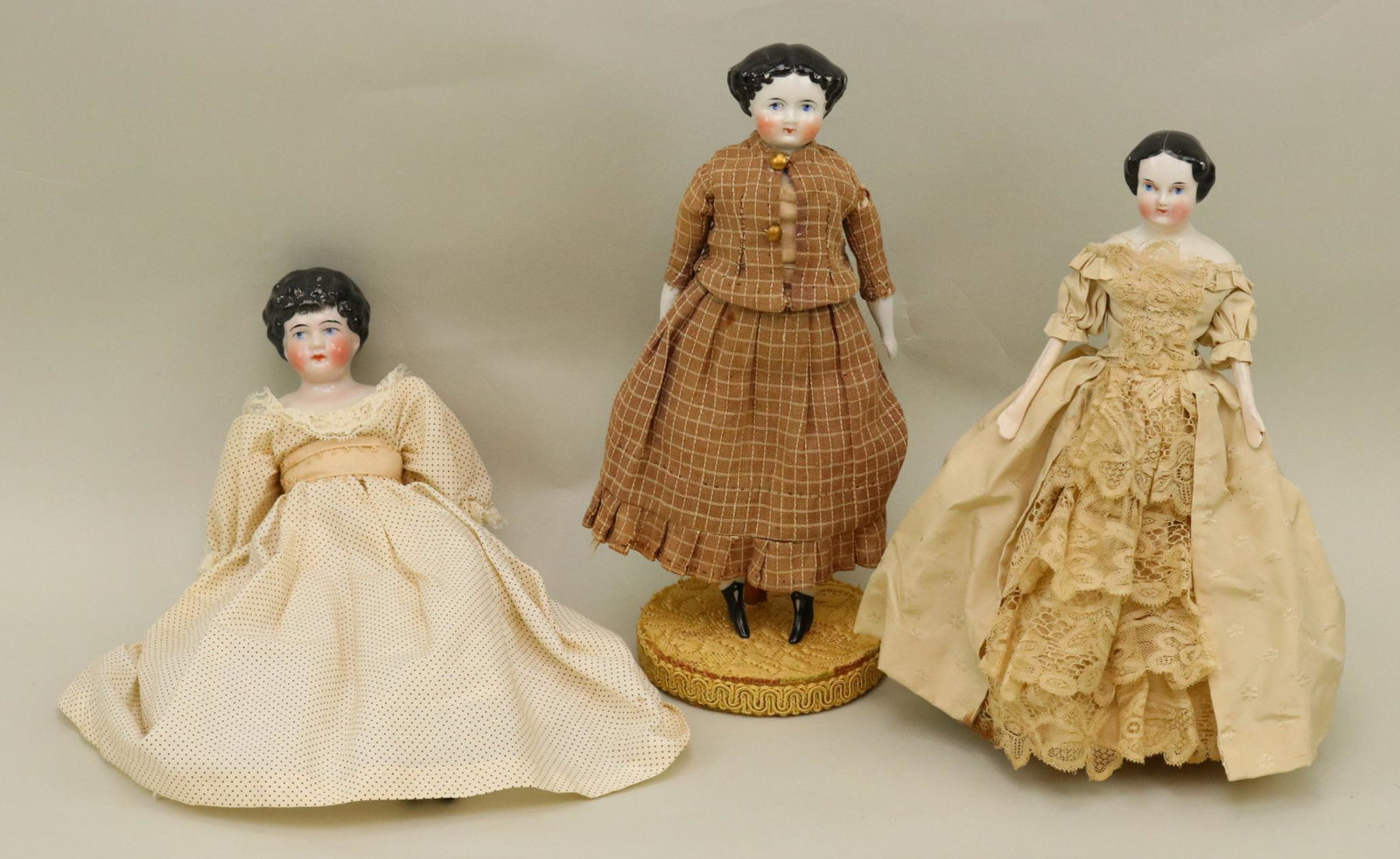 LOT OF CHINA, PARIAN DOLL(S).: Lot of (3) antique china shoulder head dolls with black hair, blue eyes. 9" Doll has an antique head with center part hair. Replaced body with wooden limbs. Silk gown. 9 1/2" Doll has an antique head 