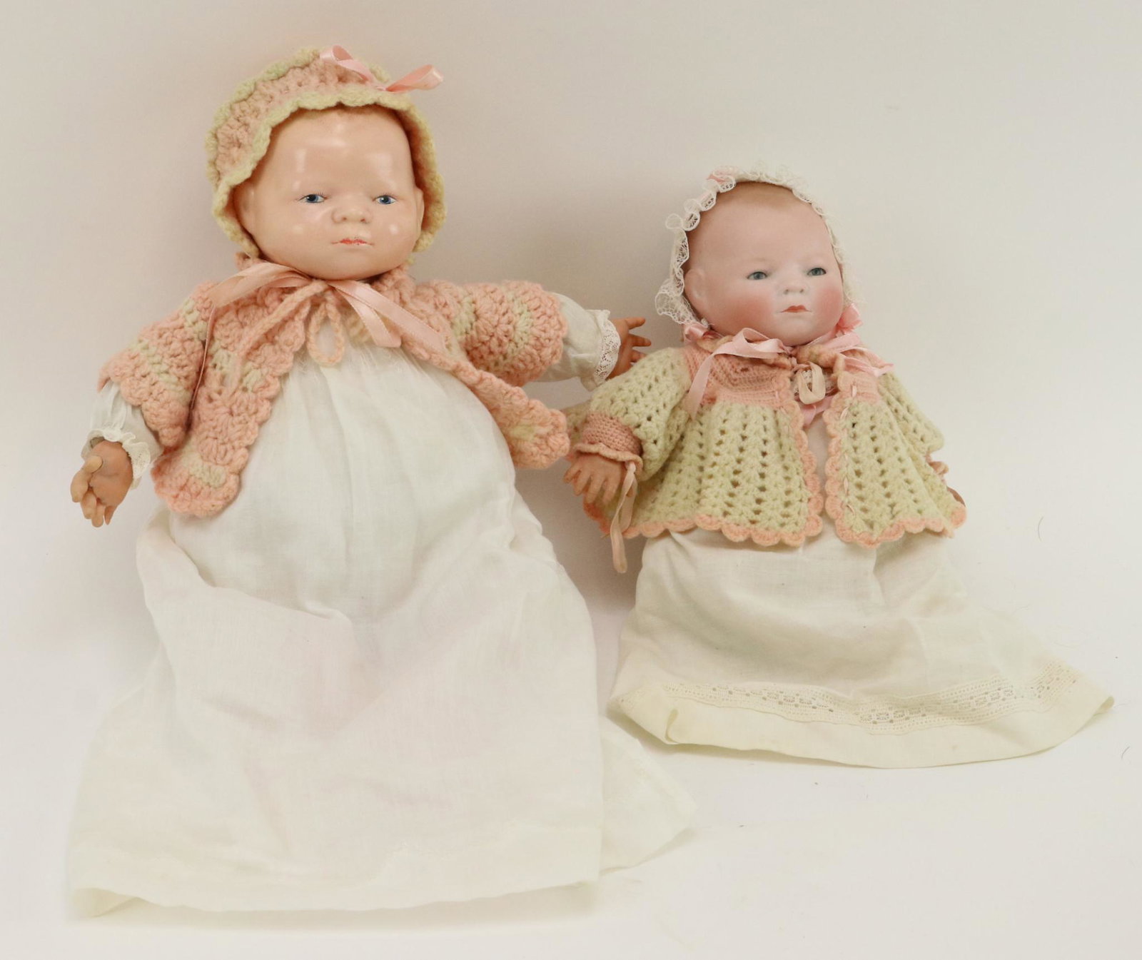 ANTIQUE GERMAN BISQUE/BISCALOID DOLL(S): Both dolls have cloth "frog" bodies with celluloid hands. They are dressed in antique gowns and have pink/ivory knit wool sweaters. Bisque - 10" L with 9 1/2" cir. head. Blue sleep eyes, closed mouth,