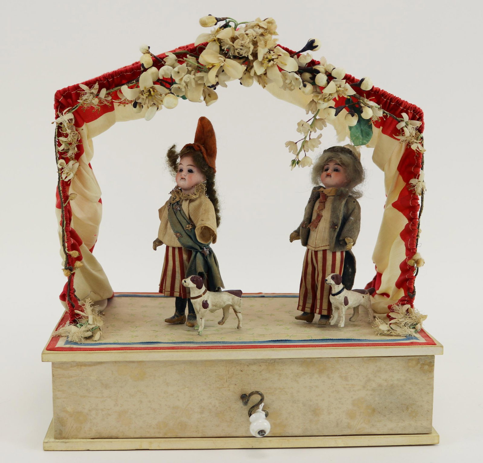 ANTIQUE GERMAN MANIVELLE.: Music box. Pair of 5 1/2" German bisque dolls standing next to their papier mache dogs. Scene represents French children under a canopy. Boy and girl with stationary eyes, open mouths, mohair wigs. 5 