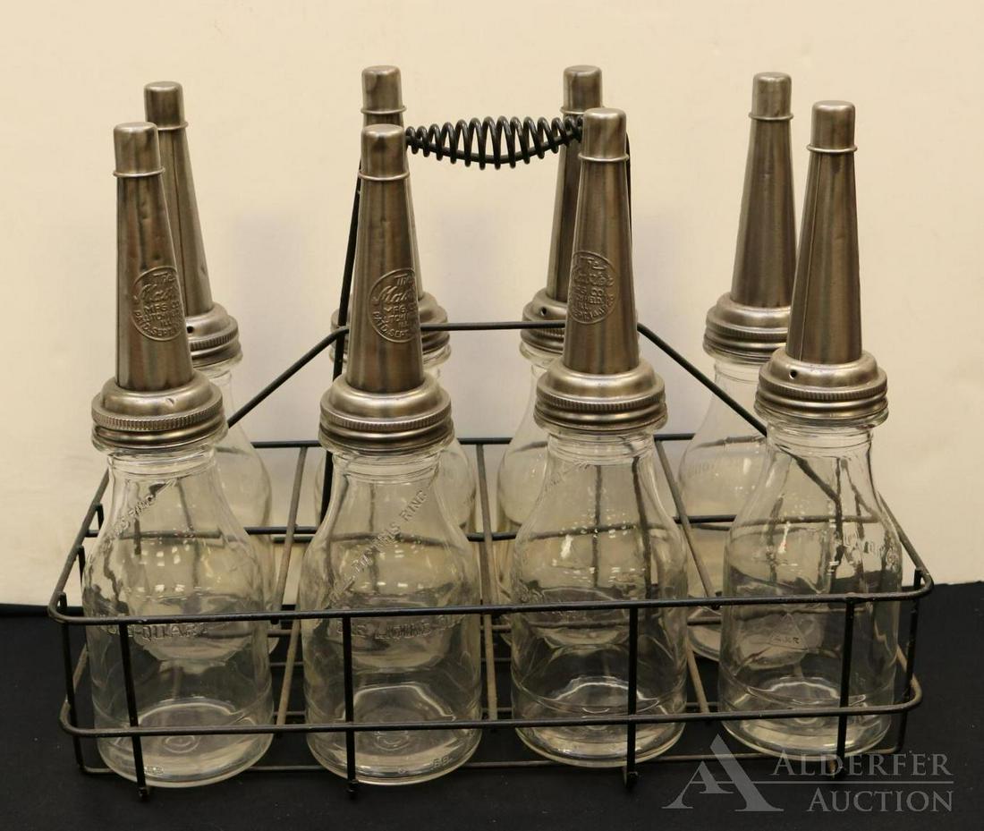 Glass Motor Oil Bottles & Carrier: Glass motor oil bottles (8) with Master pourers in carrier. Spout embossed "The Master MFG Co. Litchfield, Ill., Paid Sept. 14 1926". Bottles measures 14.25"h. Carrier measures 9.5"w x 18.75"d x 14h"