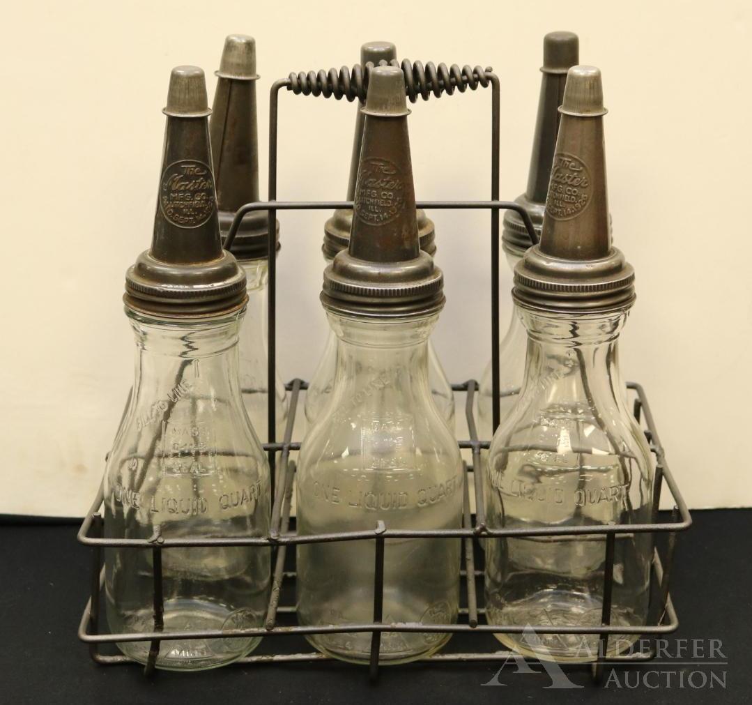 Glass Motor Oil Bottles & Carrier: Glass motor oil bottles (6) with Master pourers in metal carrier. Spout embossed "The Master MFG Co. Litchfield, Ill., Paid Sept. 14 1926". One bottle is cracked. Bottles measure 14.75"h. Carrier 9.5