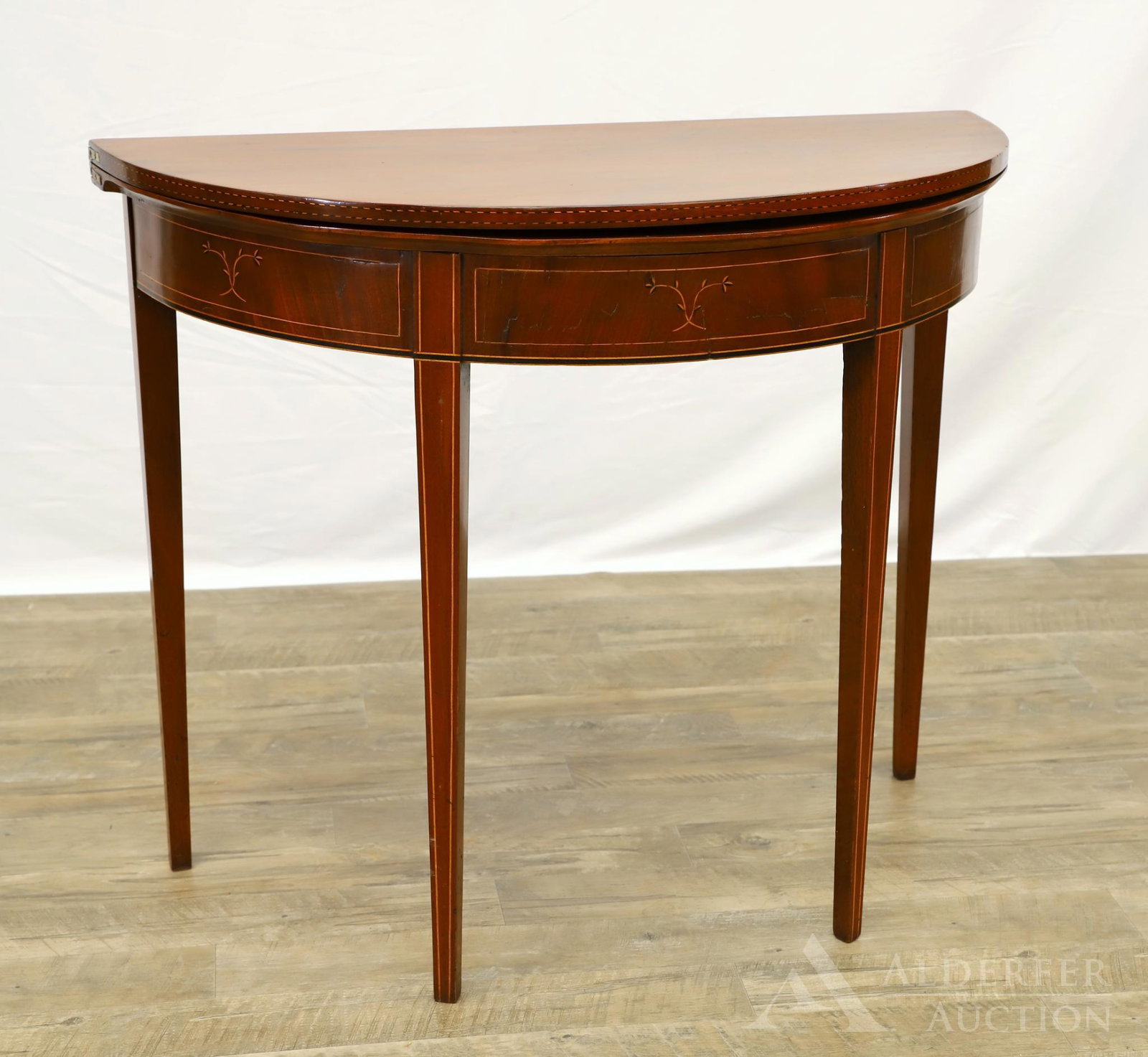 Hepplewhite Mahogany Inlaid Games Table: Demilune form opening to a circular top, banded and foliate inlay on tapered legs. 30"h x 36"w x 35"d (open)