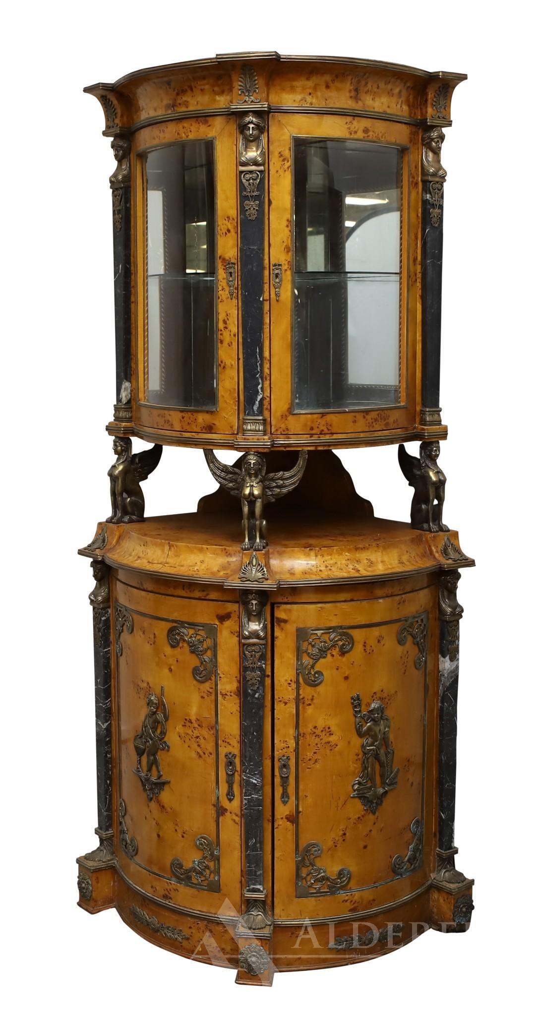 Egyptian Revival Corner Cabinet: Veneered bird’s eye maple with ormolu mount caryatid Sphinx supports, figural, and symbolic motifs with marble columns. Cylinder form with the top having a mirrored back and two glass doors over two